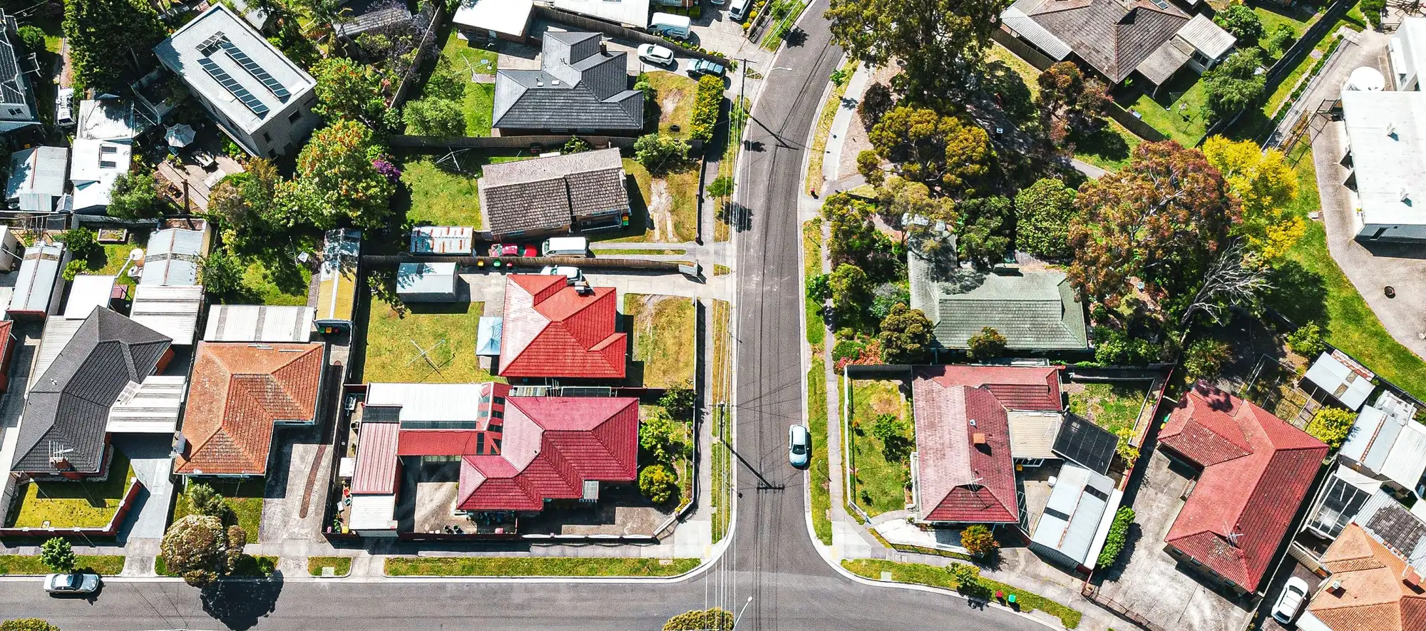 Drone view over an Australian suburb, streets and rooftops in bright daylight