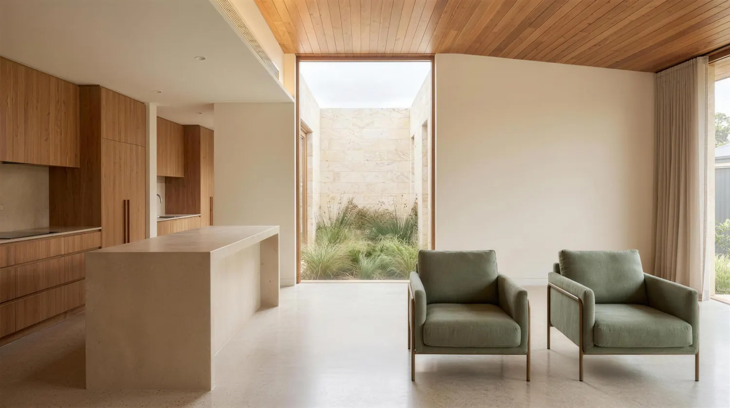 A living and kitchen space opening to a limestone courtyard planted with native grasses.
